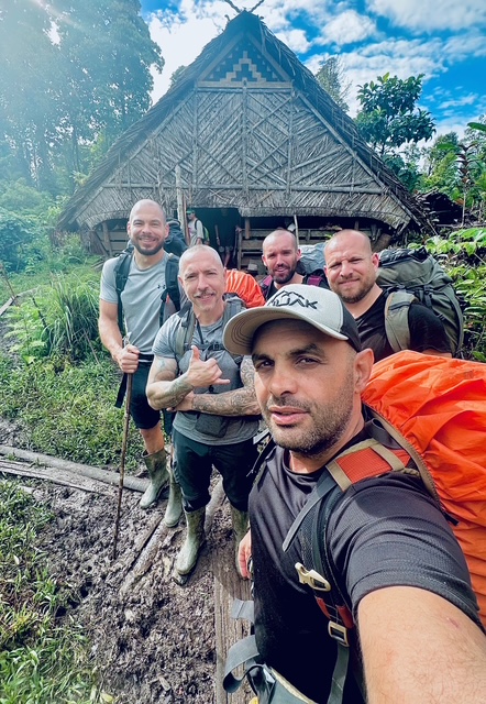 Groupe de voyageurs Anuak Adventure devant une hutte traditionnelle